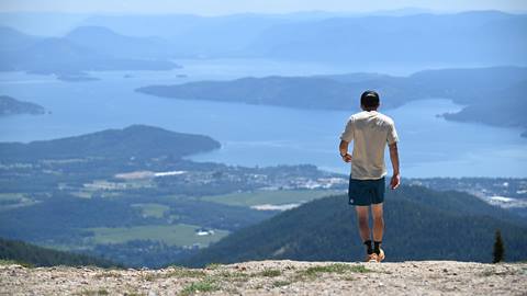 A person trail running at the summit of Schweitzer with a stunning view of Lake Pend Oreille