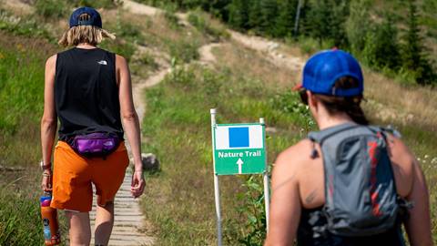 two people walking up a path with a sign that says "nature trail" at Schweitzer
