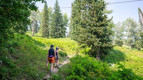 two hikers on trail walking under chairlift at Schweitzer