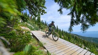 a mountain bike day ticket holder rides a wooden boardwalk trail at Schweitzer