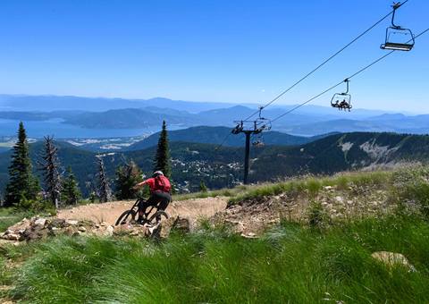 mountain biker going down trail with chairlift in the background 