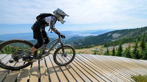 Downhill rider descends Schweitzer's elevated wooden path overlooking lake pend oreille during a mountain biking session