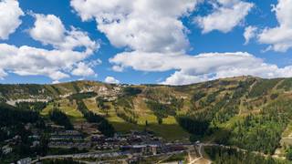 drone view of Schweitzer mountain during the summer with green grass and blue skies with some clouds
