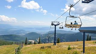 two people riding down the chairlift with views of Lake Pend Oreille