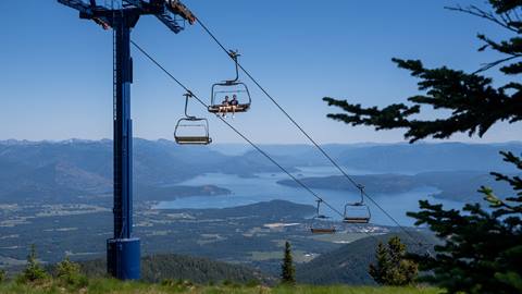 two people riding chairlift at Schweitzer during the summer with view of lake pend oreille