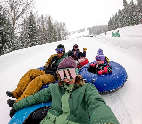 family enjoying snow tubing at hermit's hollow at schweitzer mountain resort