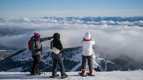 three people at summit of schweitzer snowshoeing and admiring the view