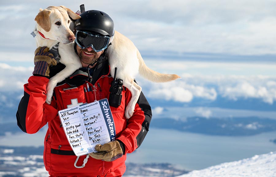 Ski Patroller Jeff with avy dog Annie on his shoulders with thier SchweitzerID cards