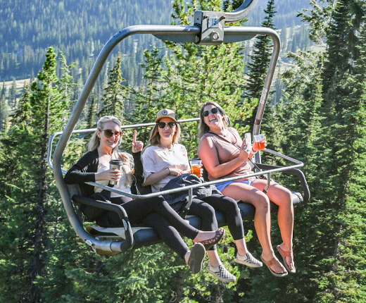 three women enjoying a beverage on the chairlift